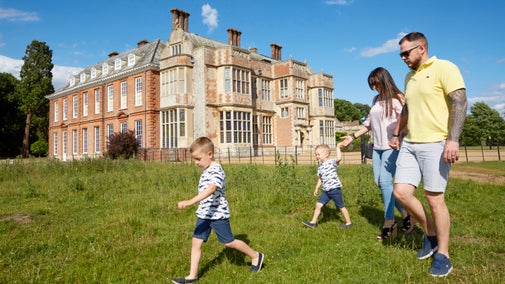 A family visiting Felbrigg walking in front of the Hall in summer